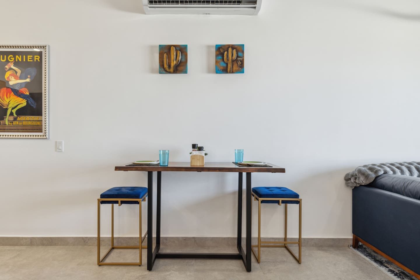 Sleek 2-stool table setting, ideal for two. Above, bold gold and turquoise metal cactus art adds a modern, stylish vibe to this Airbnb space.