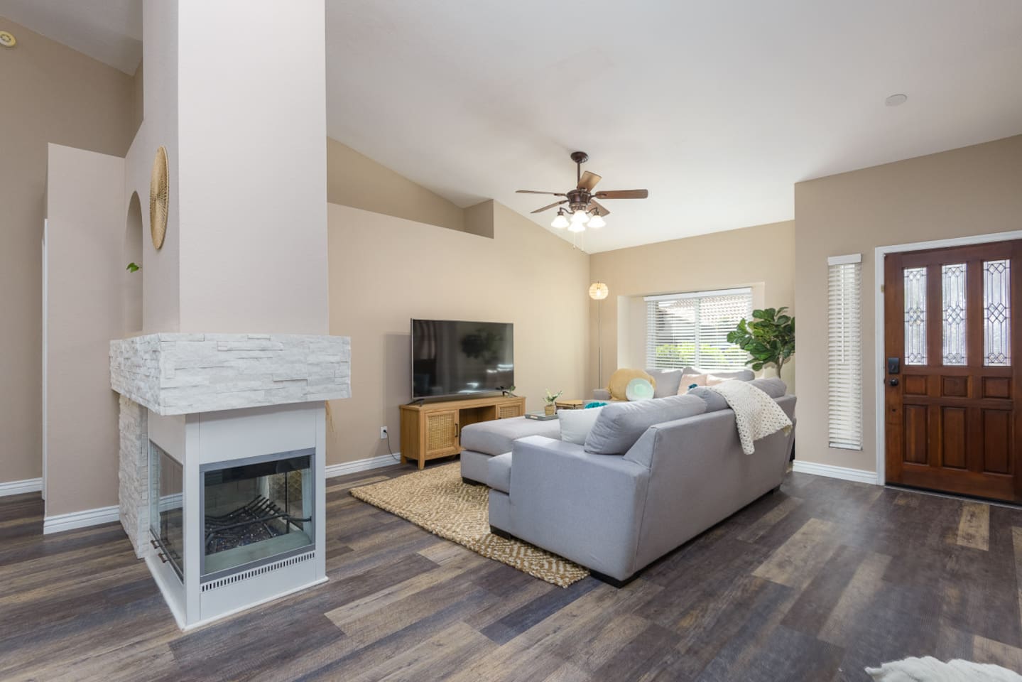 Living room with vaulted ceiling, large Smart TV, comfortable sectional seating, and room to relax or gather indoors.