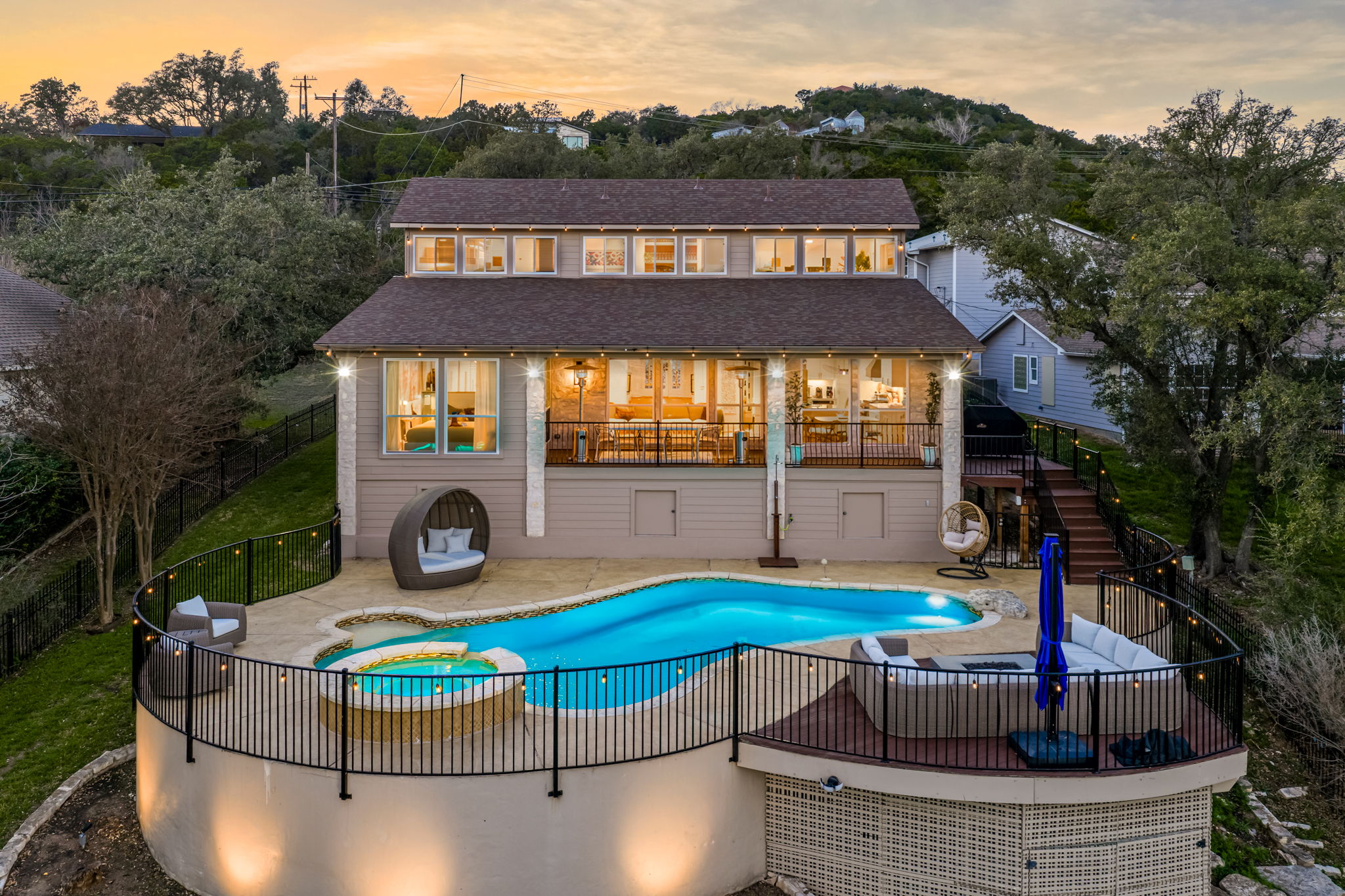 Twilight exterior showcasing the home’s elevated pool deck and lake views.