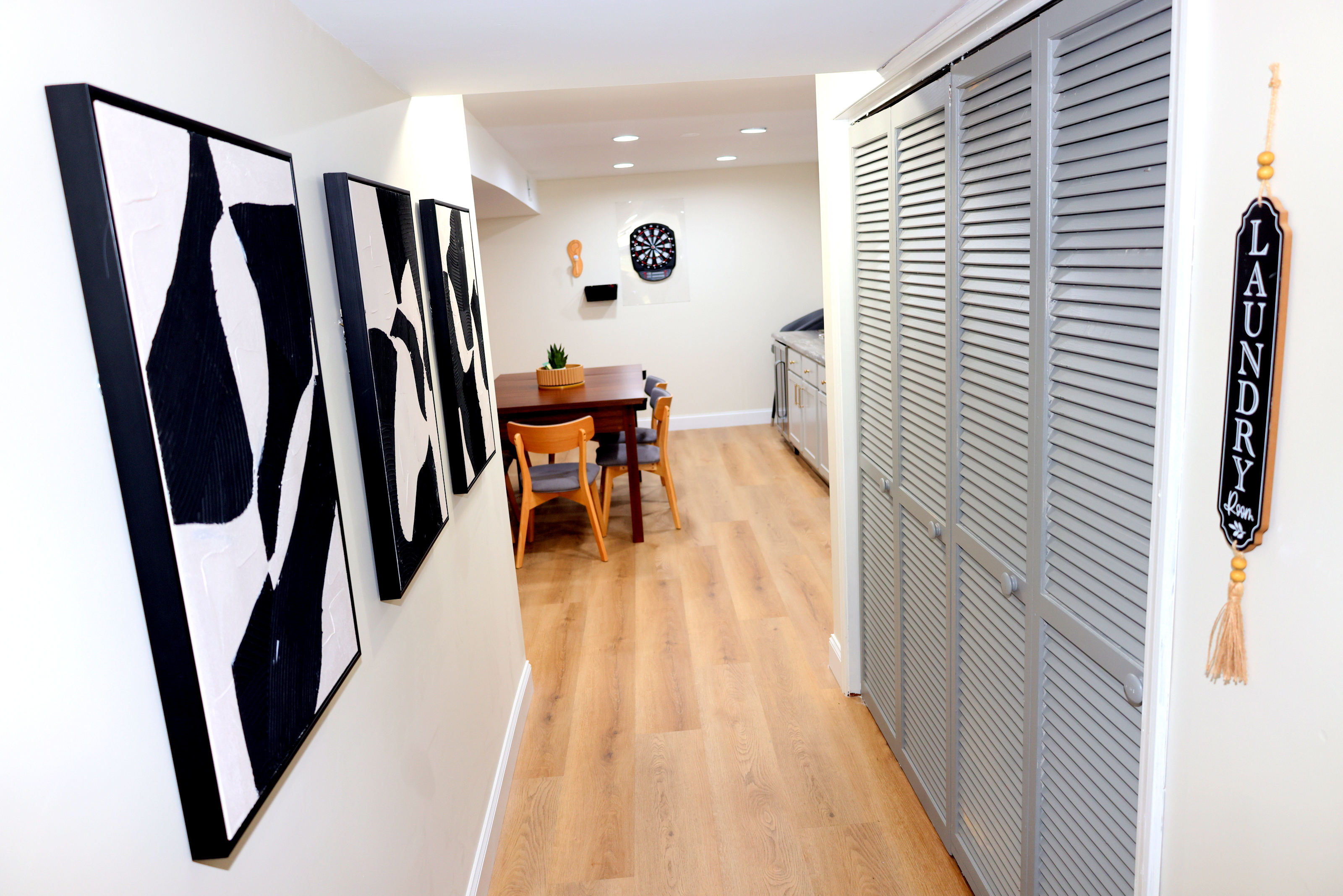 Lower-level hallway with laundry room access, game area, and stylish décor