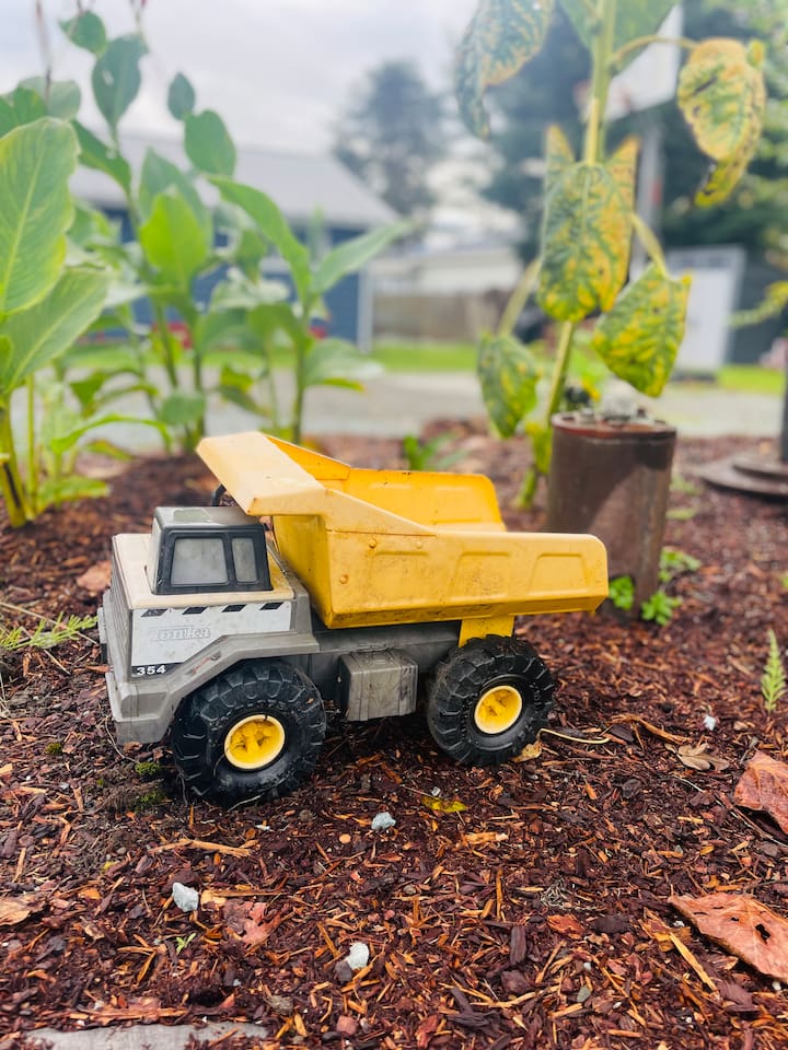 An old-style Tonka truck sits ready for imaginative excavating in the yard, inviting kids to dig, play, and explore in the open outdoor space.