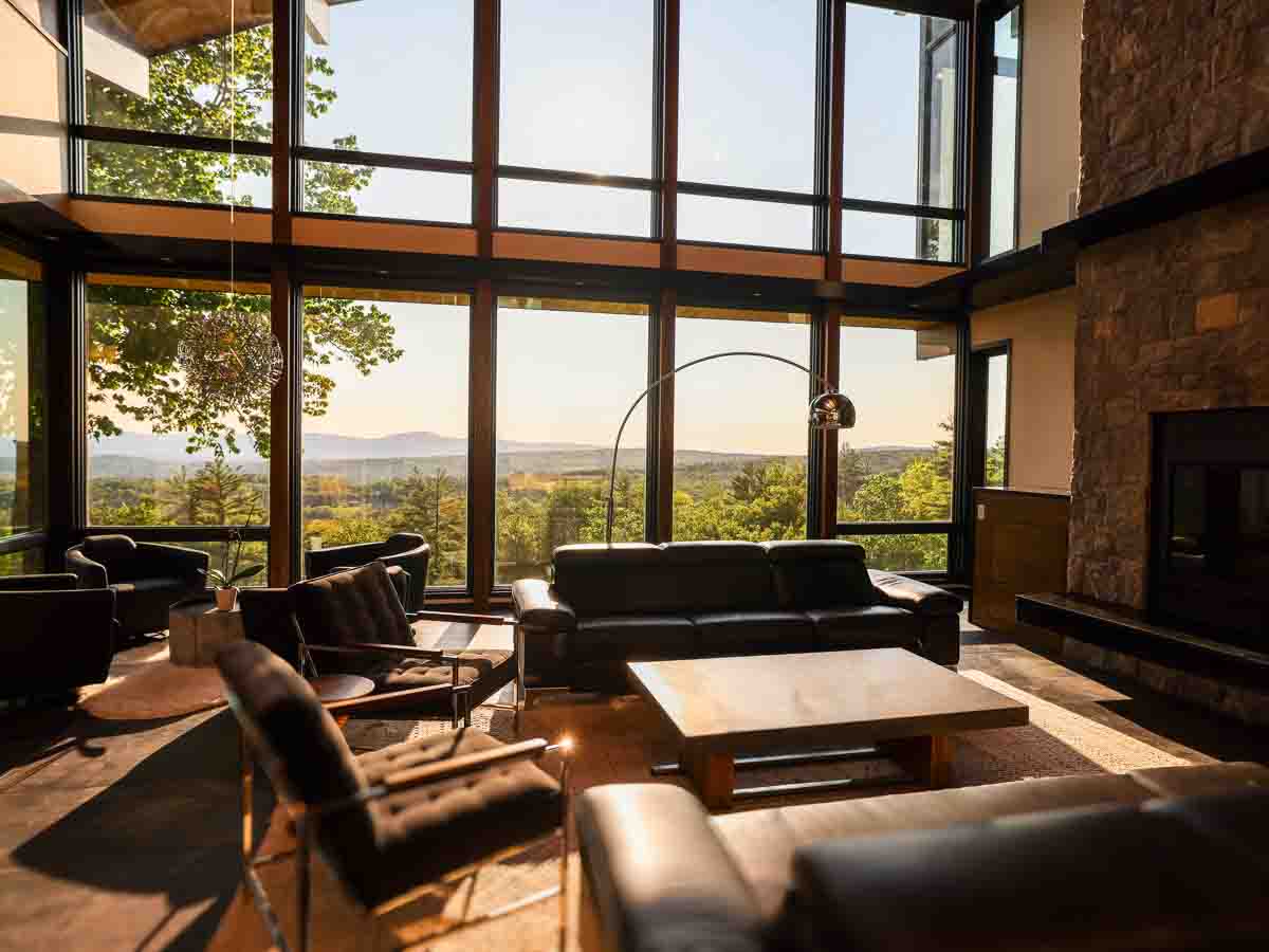 Main living room sofa seating with late-afternoon summer sun through floor-to-ceiling windows &mdash; Sunset Falls Berkshires