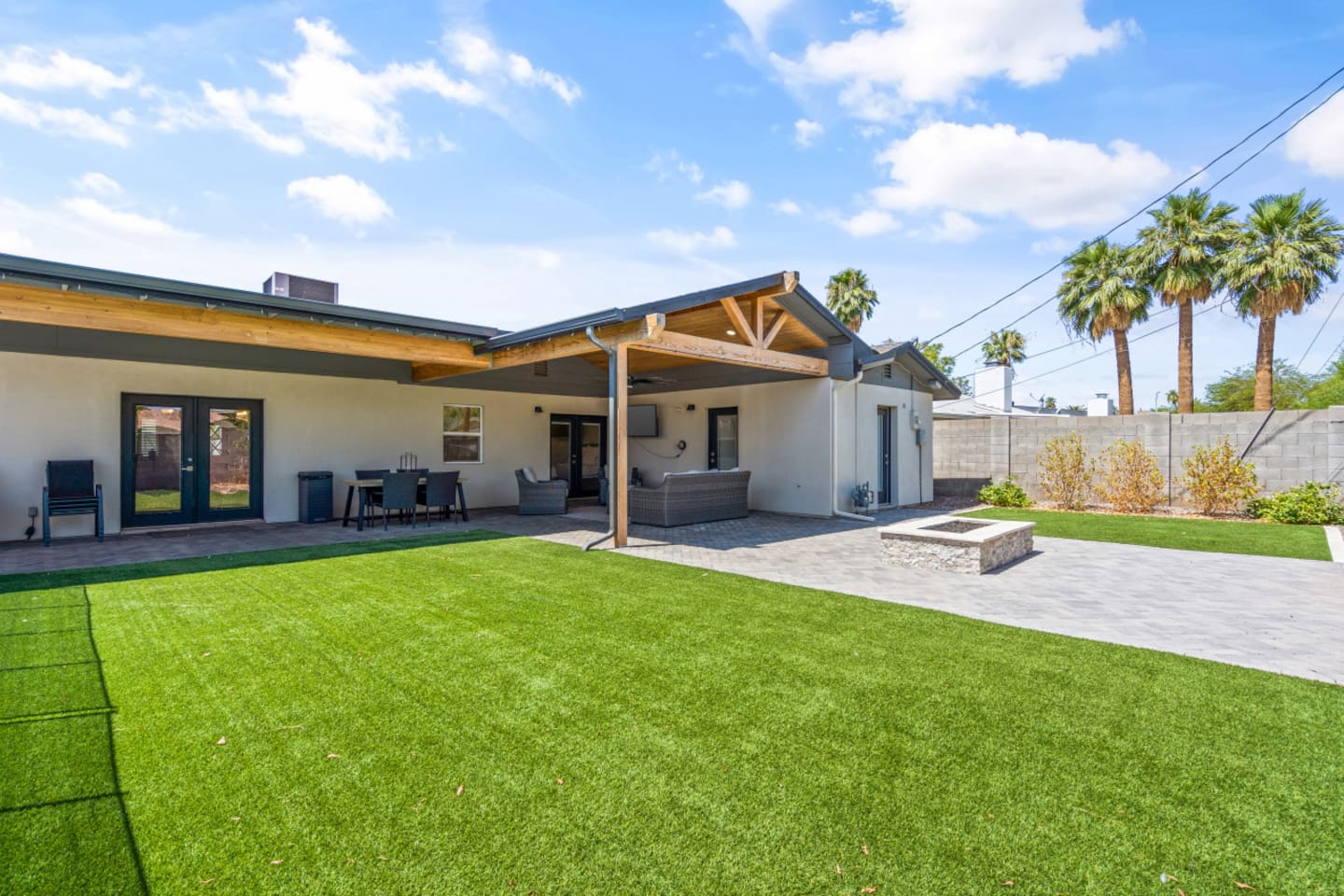 Outdoor living area with shaded lounge space, fire pit, and a clear view toward the pool.