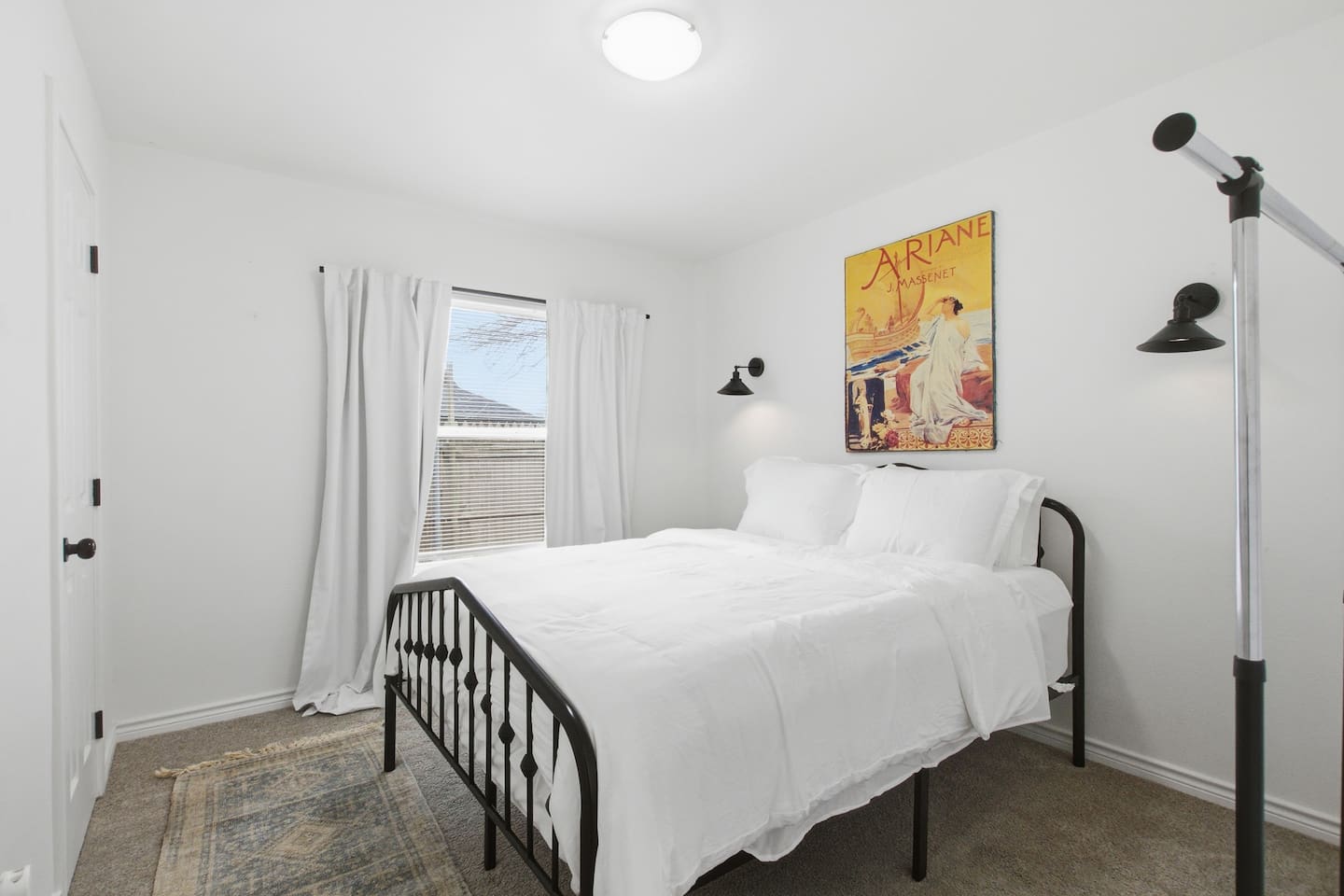 Bright guest bedroom featuring a queen bed, soft bedding, natural light, and room darkening shades for comfort and privacy.