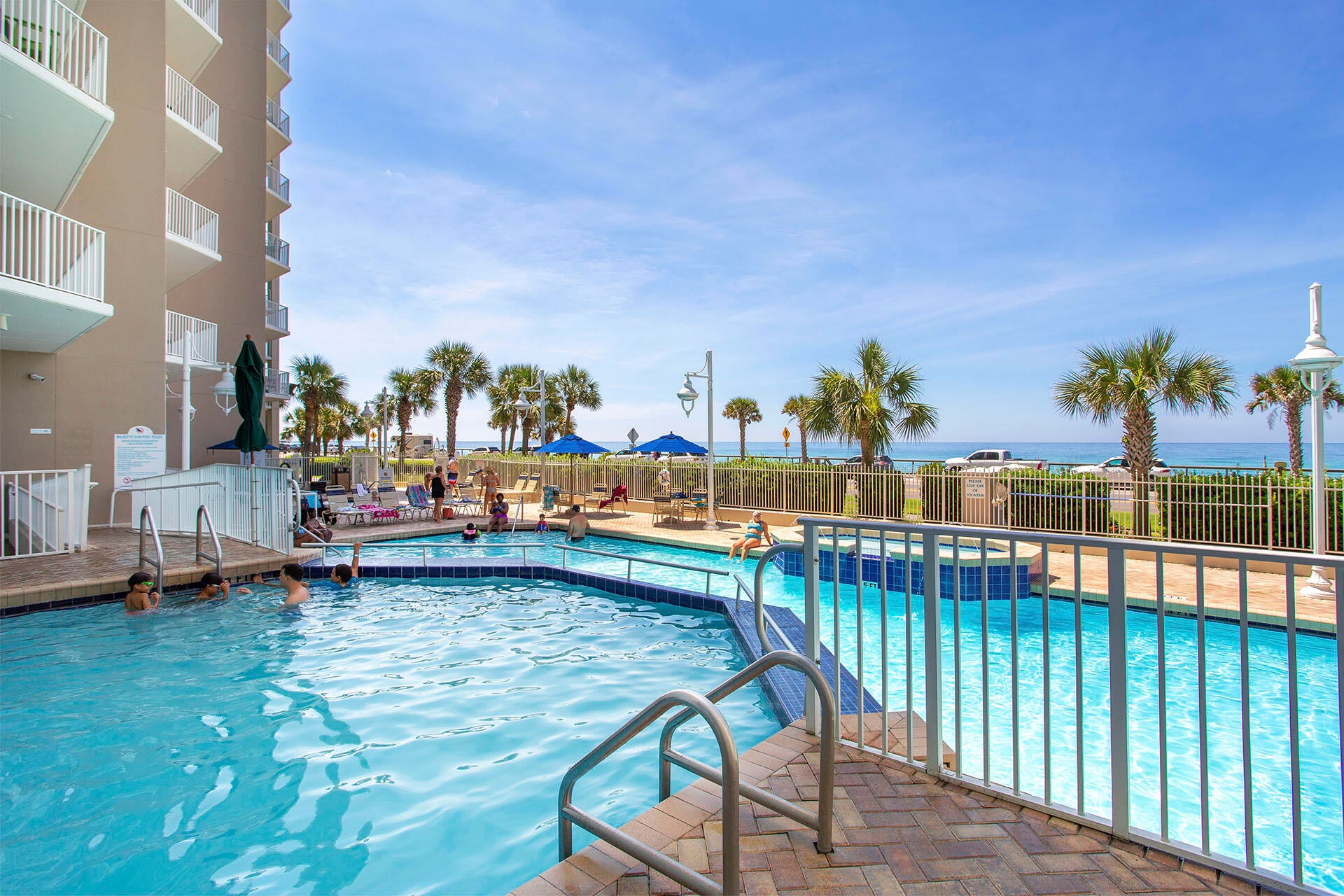 Resort-style pool w/ lounge chairs, palm trees & a relaxed spot to cool off under the sun.