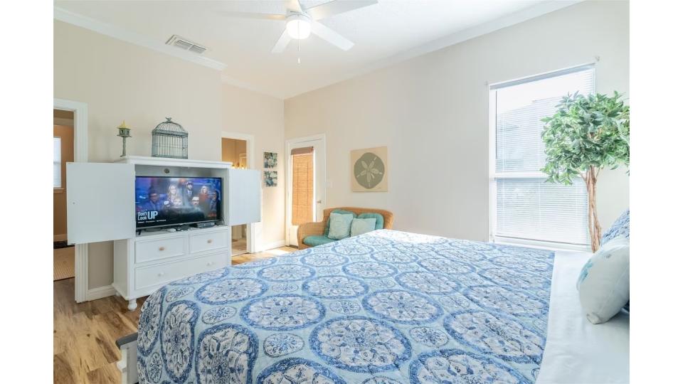 Upstairs King Master Suite with private balcony access. This serene bedroom offers plenty of natural light, ceiling fan for comfort, coastal decor, and your own HDTV. Step outside to the balcony for morning coffee with ocean breezes or evening stargazing.