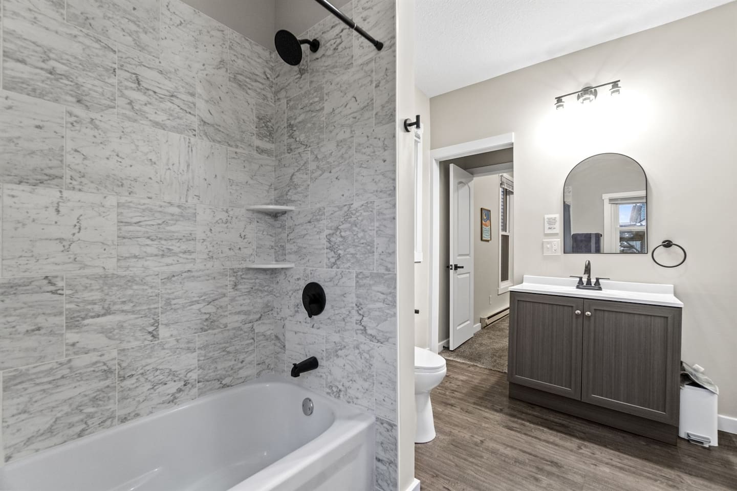 Modern tile shower/tub combo paired with a spacious vanity offering plenty of room for toiletries.