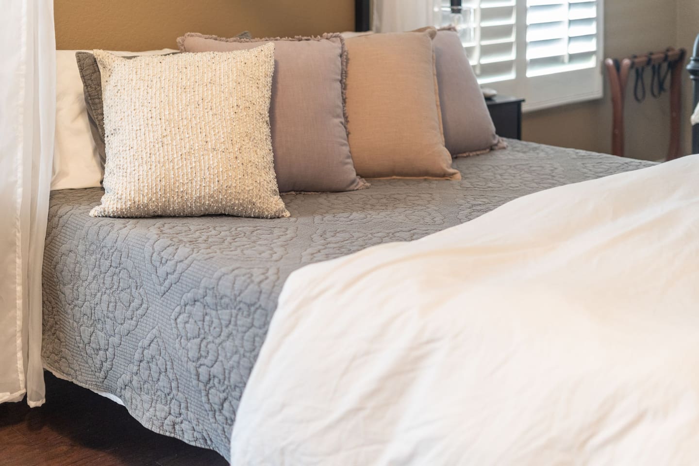 Soft layered pillows and a textured coverlet give the queen bed a cozy, well-dressed feel — the kind of bed that makes it hard to get up in the morning.