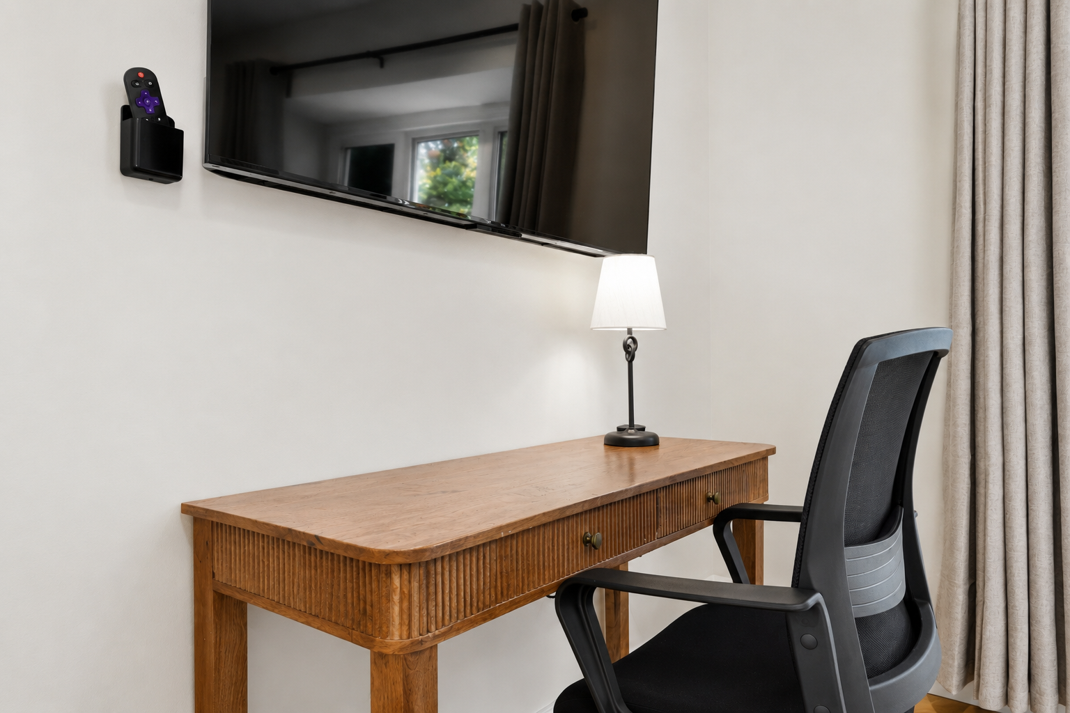 Modern workspace with a sleek desk and ergonomic chair, perfect for remote work or study with a wall-mounted TV nearby.