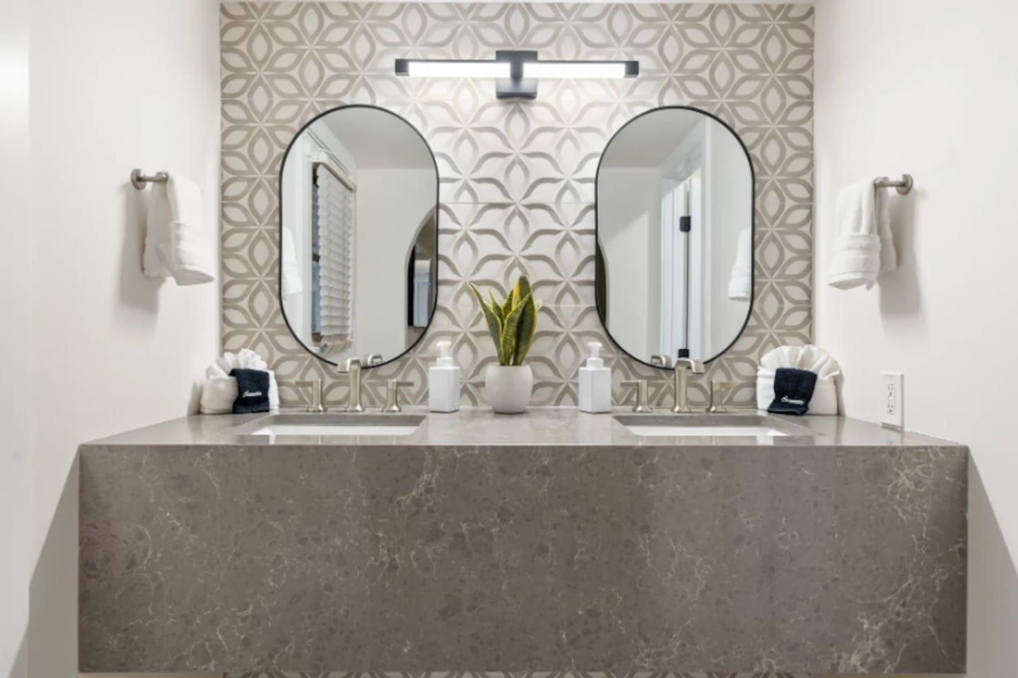Two oval mirrors and a floating stone vanity make morning routines feel a little more indulgent. Fresh greenery and soft lighting add the finishing touch to this refined space.
