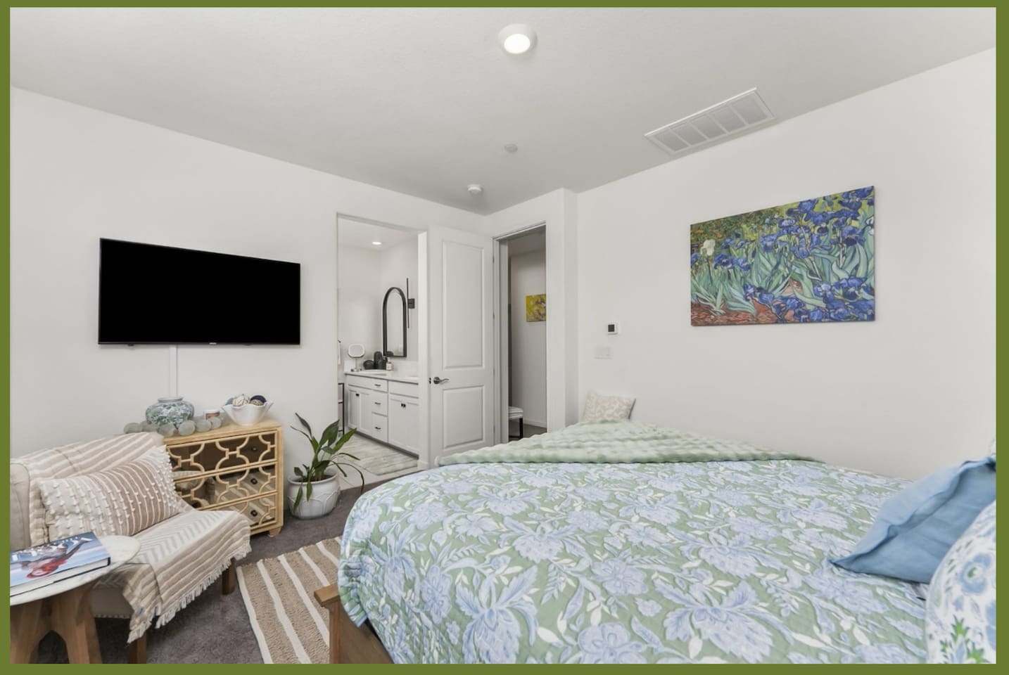Bedroom with queen bed, mounted TV, accent chair, and relaxing aesthetics for a comfortable stay.