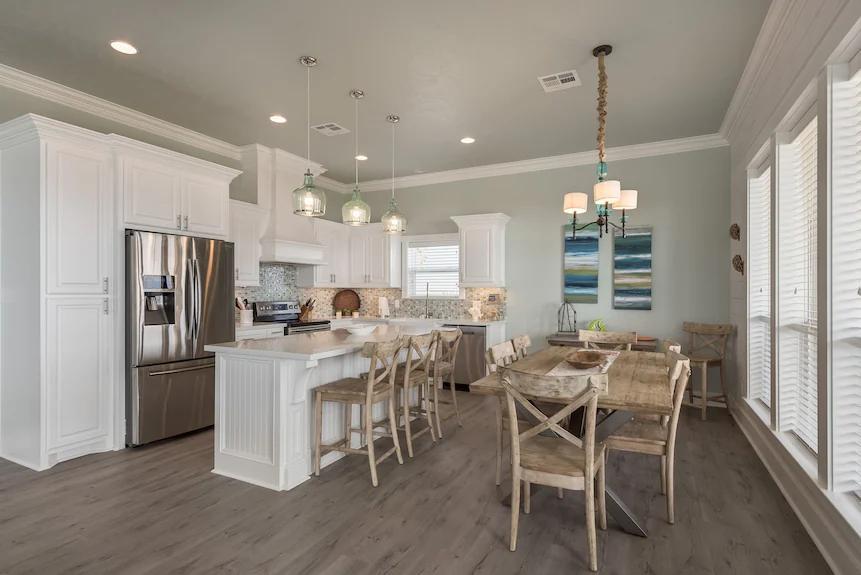 Cook in comfort with a huge island, elegant pendant lighting, and easy access to the dining area, all while enjoying the bright, breezy ambiance of this coastal home.