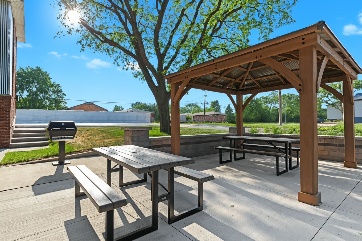 Shaded pergola with picnic tables and adjacent grill stations for dining al fresco.