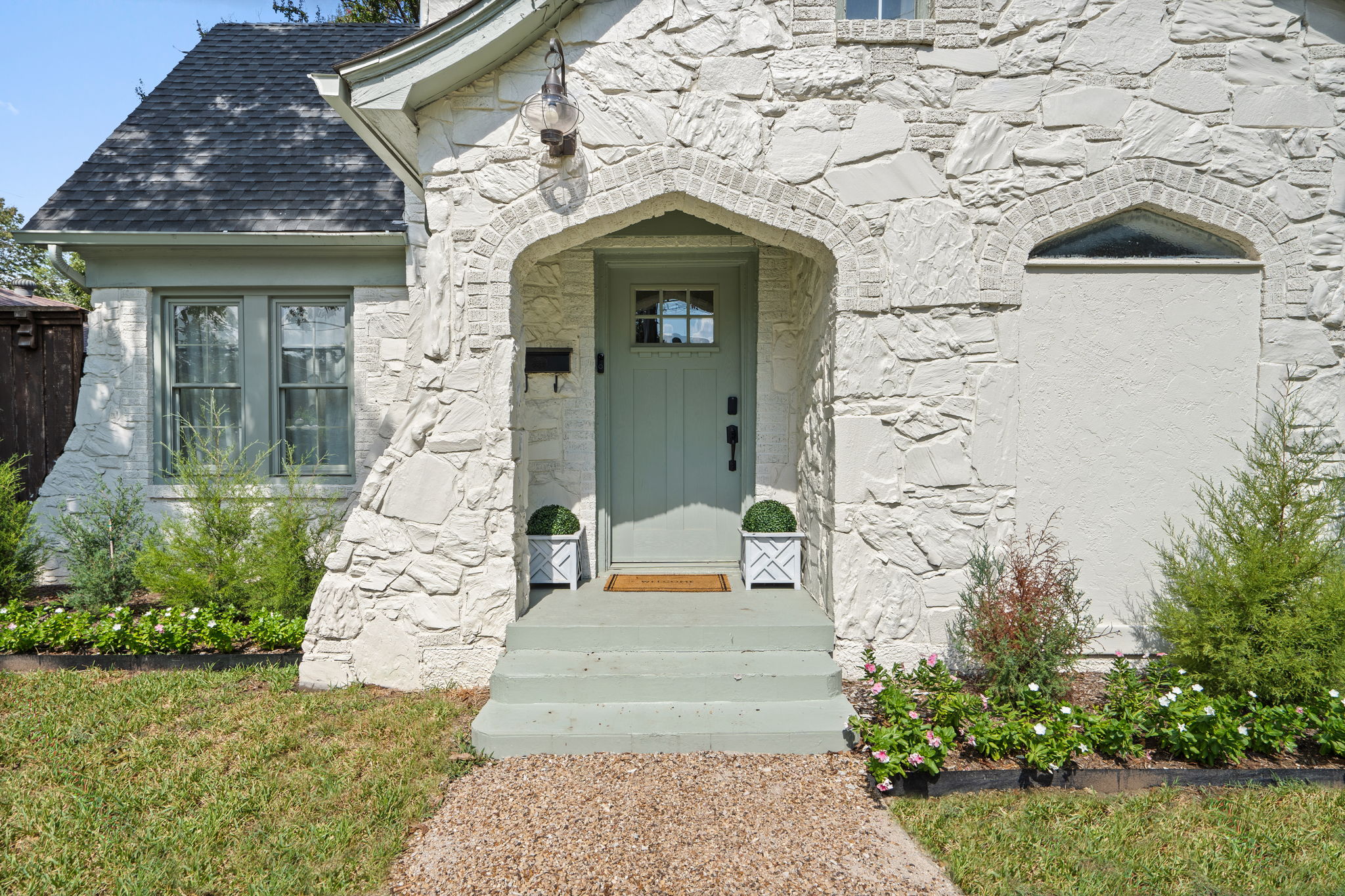 Sage green front entry door set into original 1929 stonework. Covered entry with lush surrounding landscaping and classic Dallas architectural character. Welcome home!