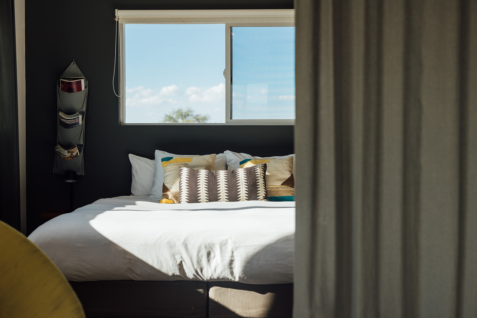 Inviting bedroom with queen bed and curtain partition for added privacy, blending modern comfort with rustic charm.