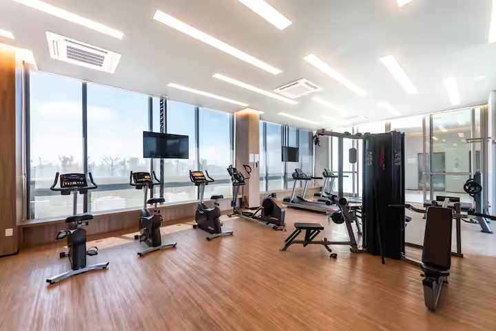 💪 Academia completa com equipamentos de musculação e esteiras, e janelas panorâmicas.