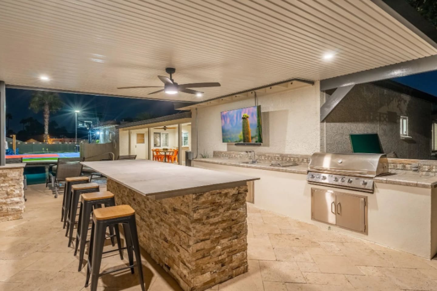 The outdoor bar seats the whole crew, with a built-in grill and big screen — this is where the party actually happens.
