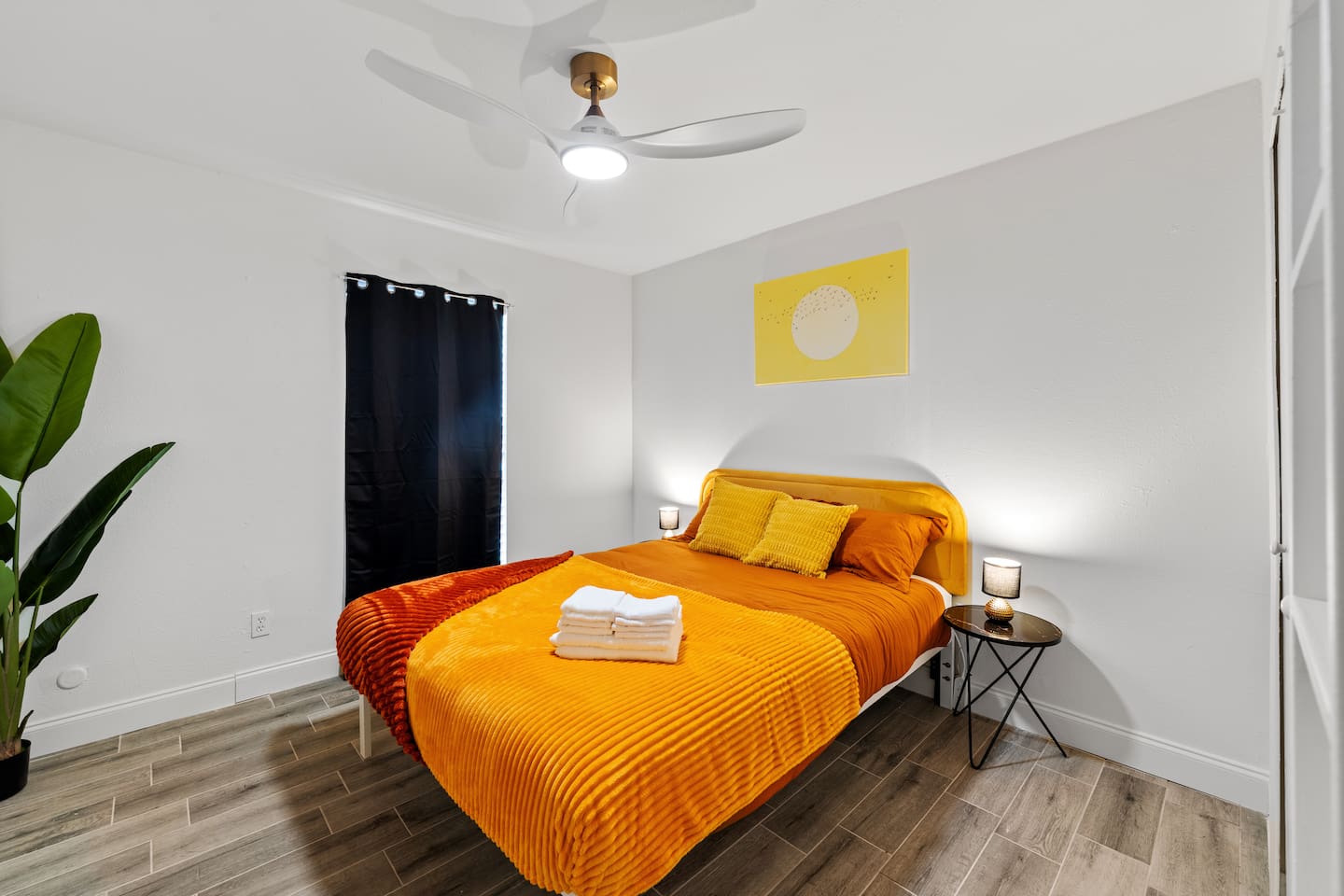 Bright bedroom with cozy orange bedding, blackout curtains, and ample closet space—perfect for restful nights and relaxed mornings.