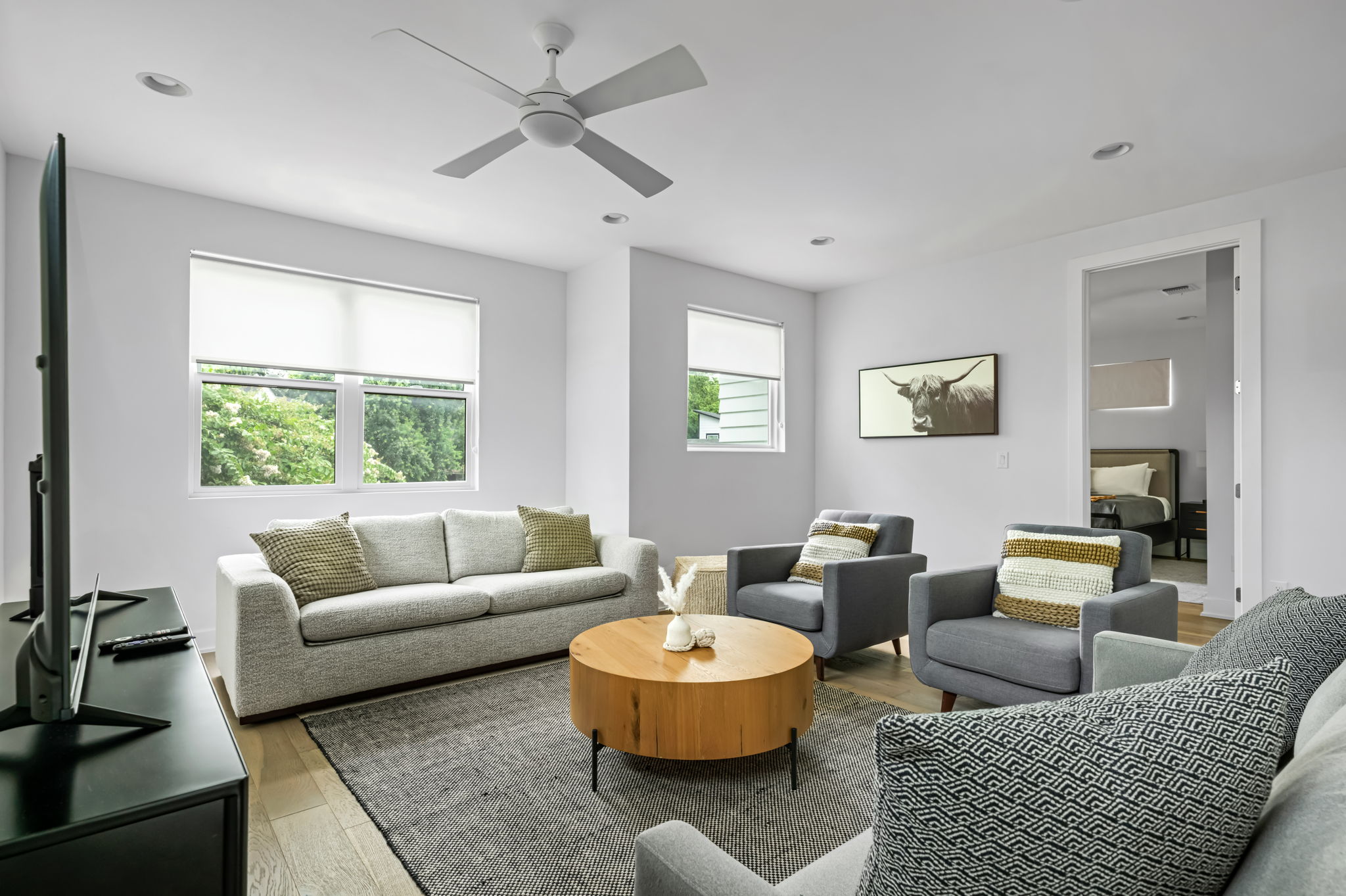 Comfortable second living space with modern gray furniture and large windows — ideal for kids' movie nights or extra lounge space.
