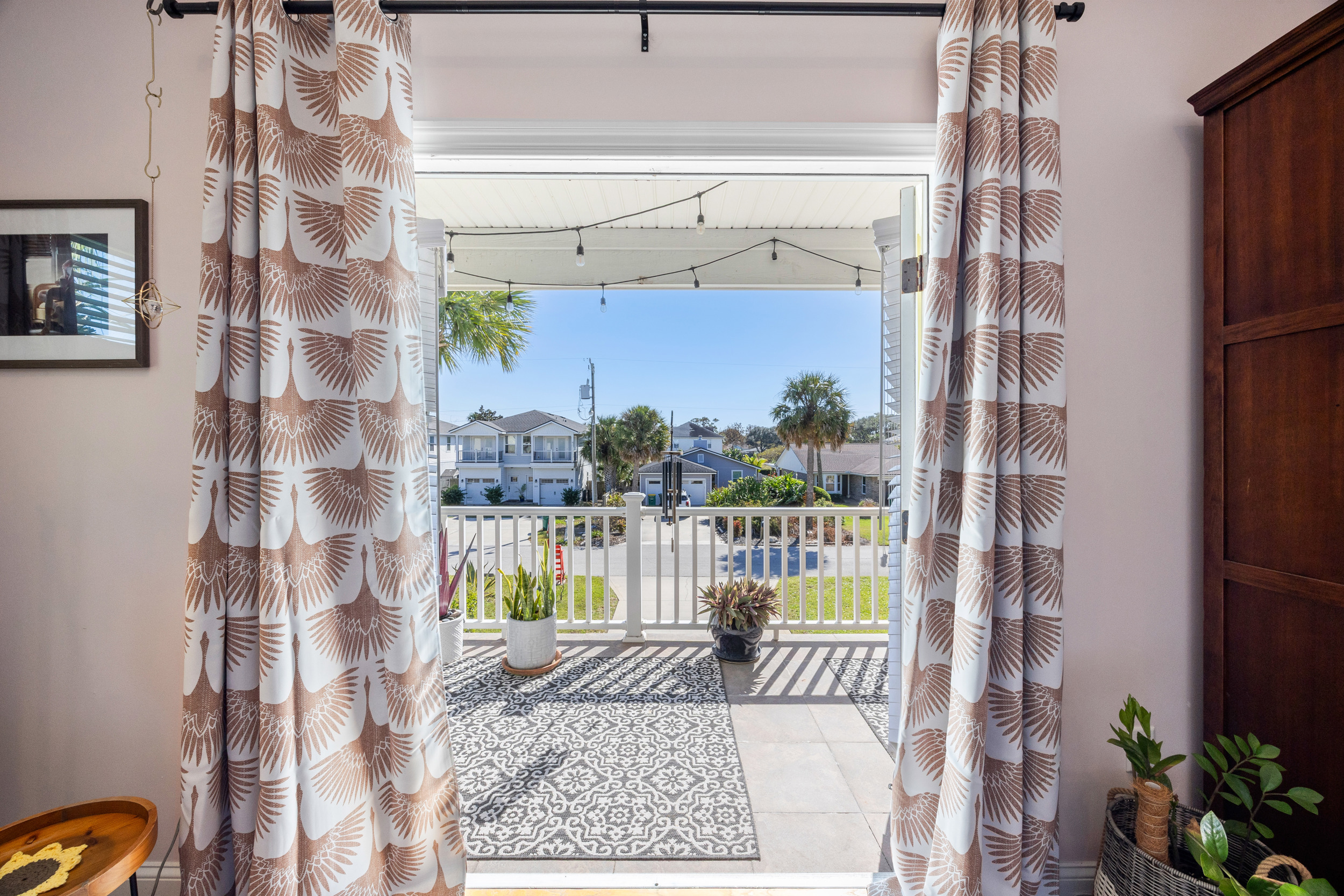 Indoor‑outdoor view from bedroom to porch with plants and string lights in Jacksonville Beach vacation rental.