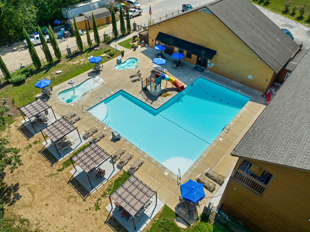 Resort style pool with waterslide, hot tub, and plenty of seating.
