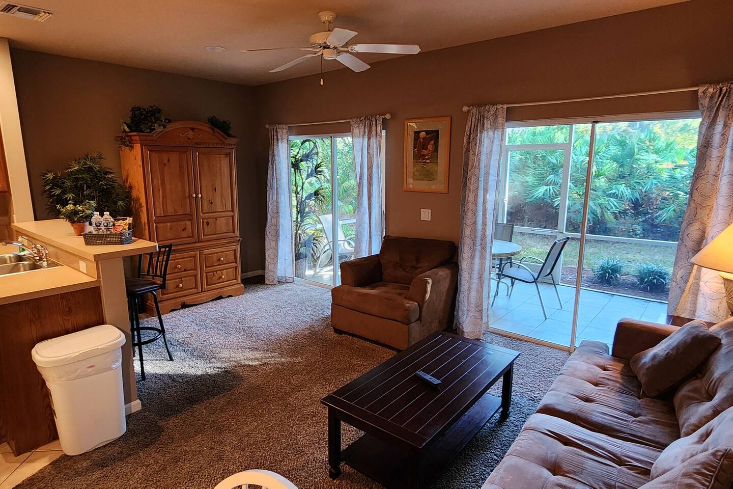 Spacious living area with comfortable seating, large windows, and sliding glass doors leading to the private screened patio.