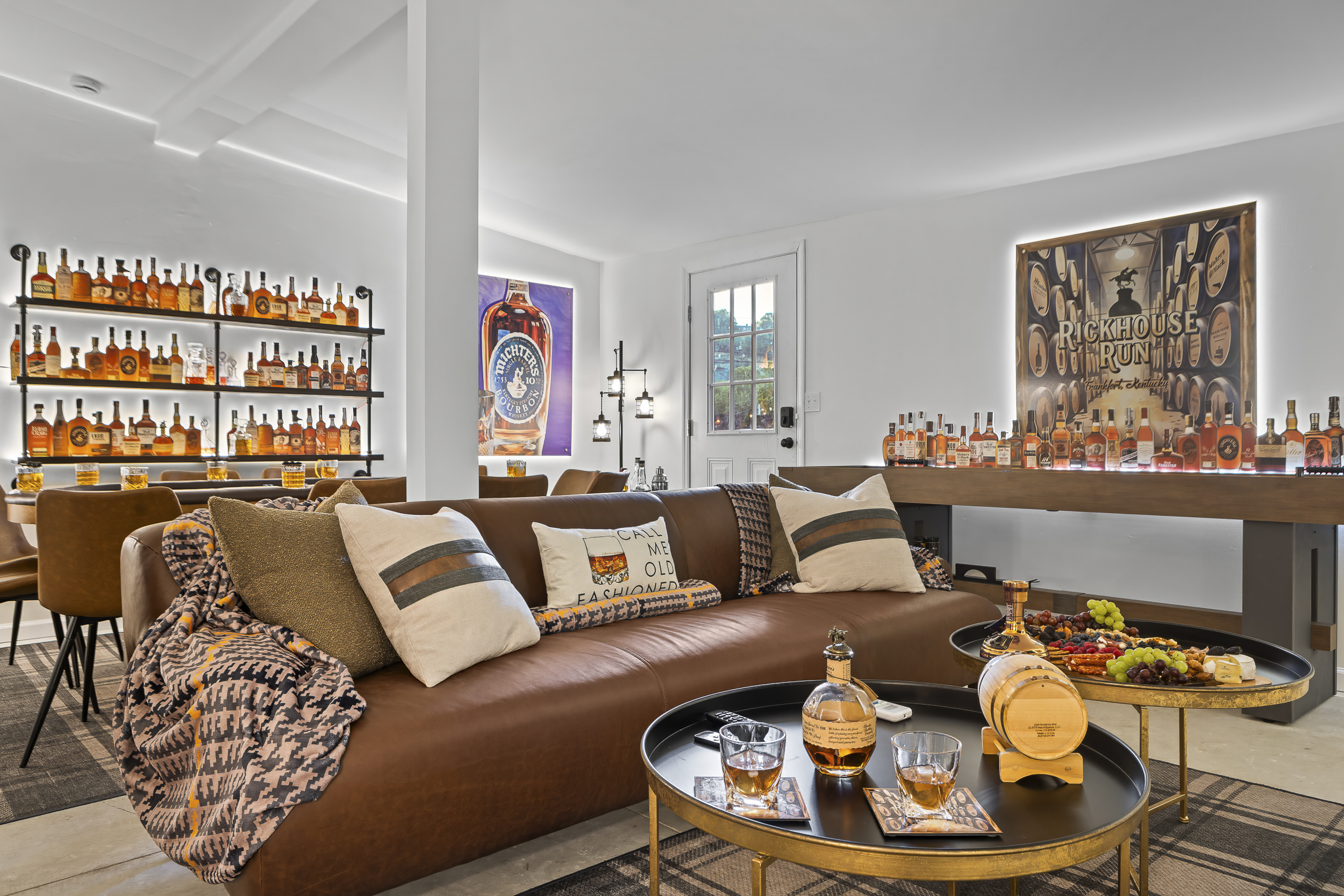 Two leather sofas, a full bourbon display wall, and the Rickhouse Run sign set the tone for a game room designed to impress.