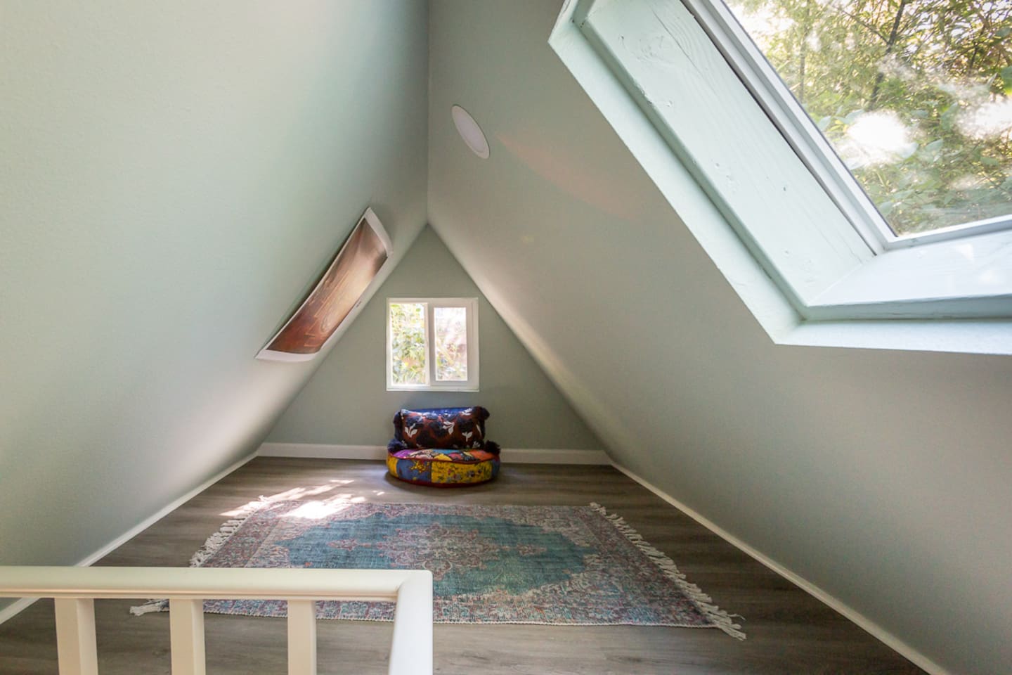 - Cozy loft nook with vaulted ceiling and large skylight for natural light
- Soft area rug creates a welcoming spot for reading or quiet retreat
- Unique triangular architecture adds charm and character to the space
