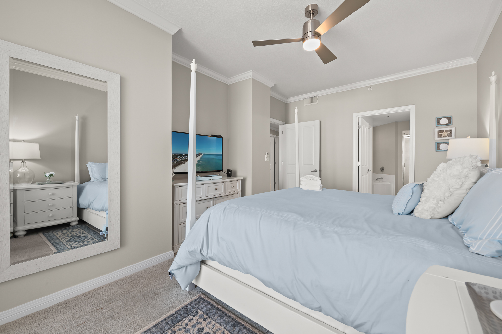 Primary bedroom w/ TV and simple coastal design for easy relaxation.