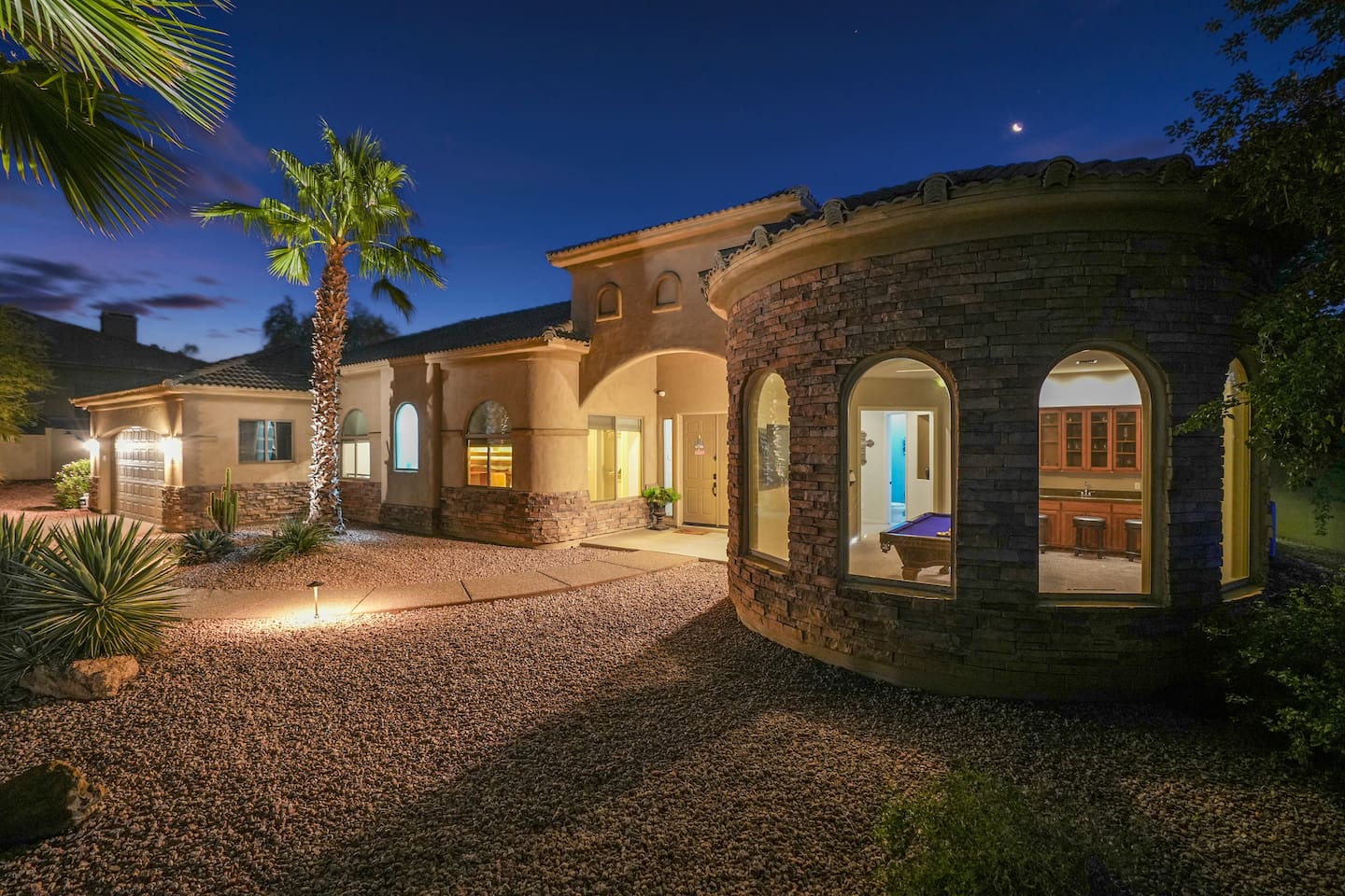Front of the home featuring elegant architecture, stone accents, and soft nighttime lighting that creates a warm, welcoming first impression.