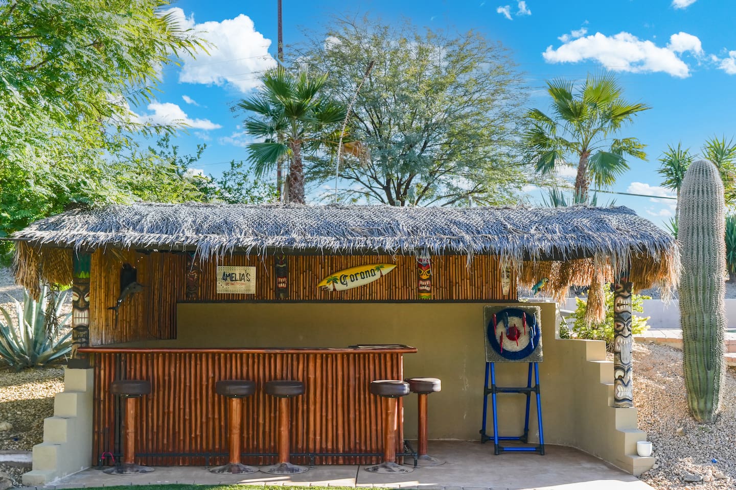 Tropical-style outdoor bar surrounded by desert landscaping and palm trees for a resort-like feel.