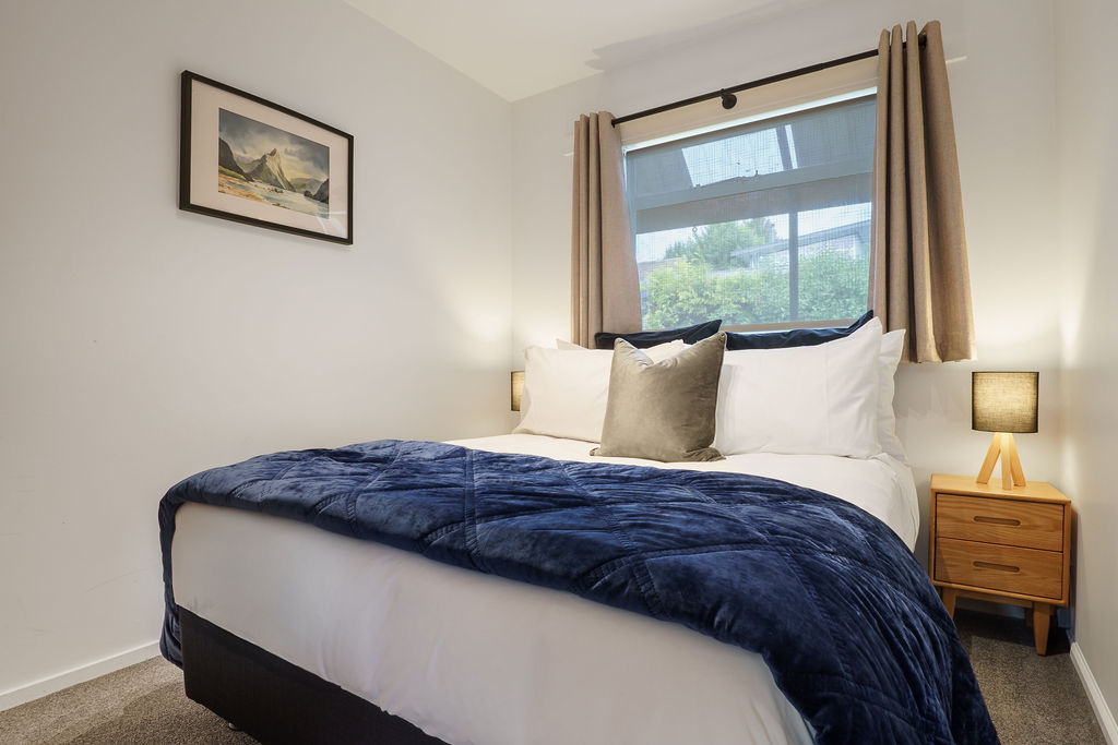 This bedroom includes a queen bed, bedside lighting and soft layered bedding, giving Fernhill Mountain Escape another comfortable room for guests.