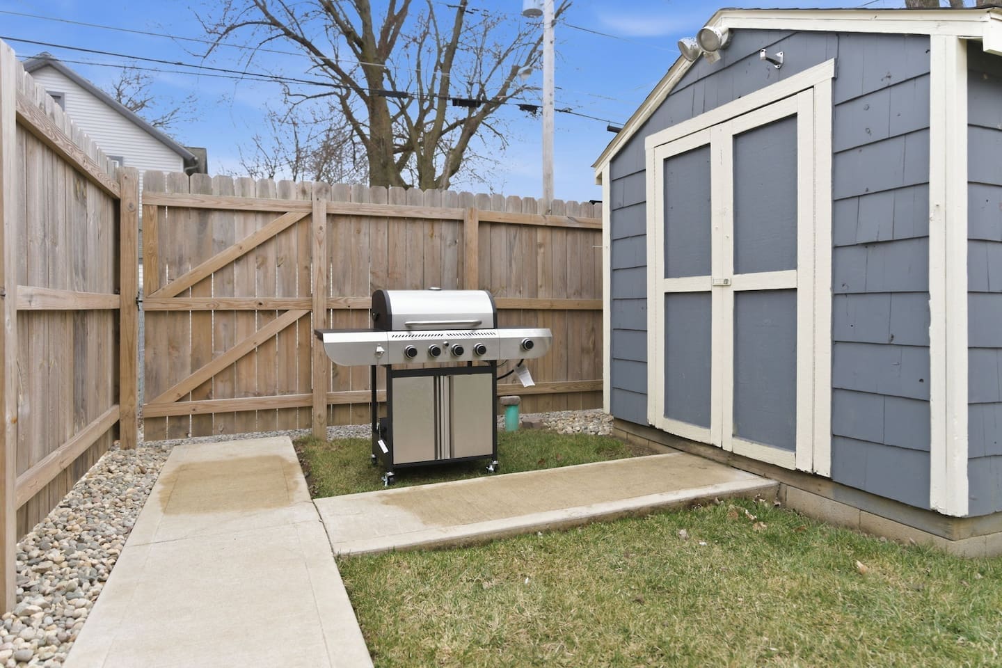 Backyard setup with grill and storage shed, perfect for outdoor cooking and convenience