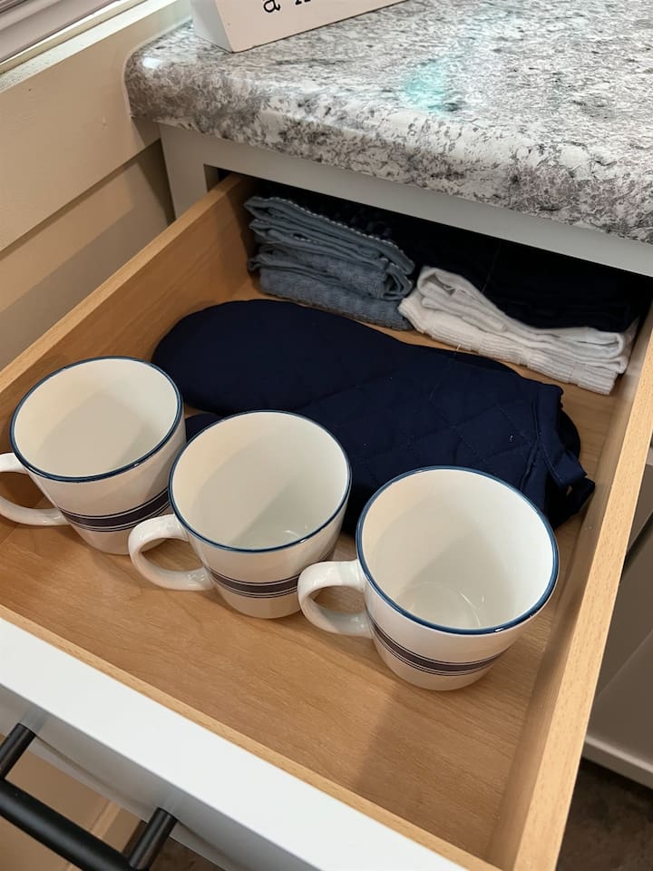 Fully equipped kitchen featuring a cabinet with neatly organized cups, a rag for the granite table, and a stylish design that blends practicality with modern elegance—perfect for an organized and functional cooking space