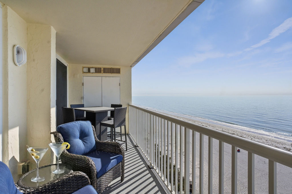 Spacious private beachfront balcony with comfortable lounge seating, outdoor dining area, and panoramic ocean views, perfect for morning coffee or evening cocktails by the water.