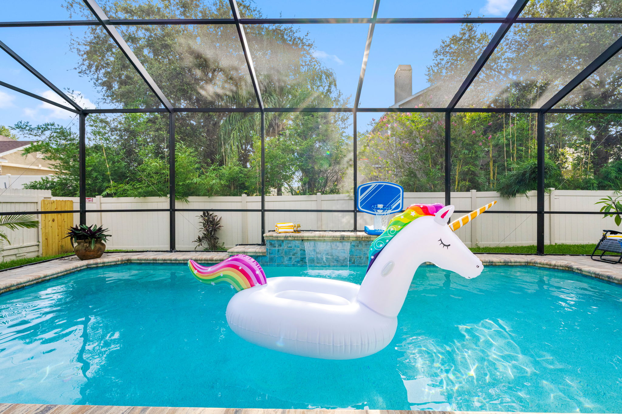 Dive into vacation mode in this serene, screened-in pool featuring a cascading waterfall and a playful atmosphere for guests of all ages.