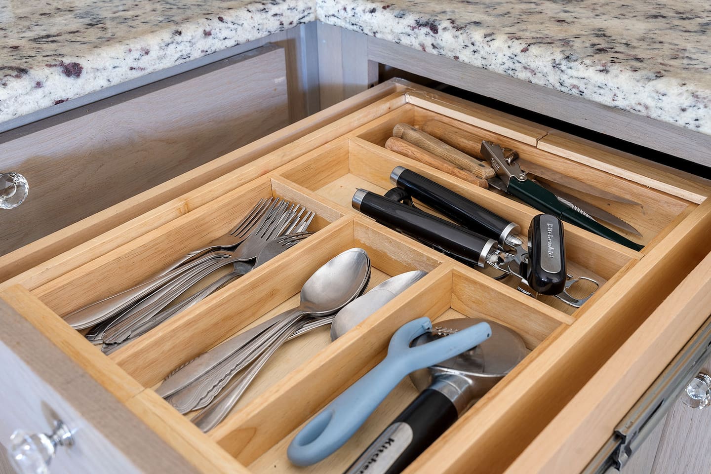 Discover a well-organized kitchen drawer featuring a variety of utensils and tools. With everything from cutlery to essential gadgets neatly arranged.