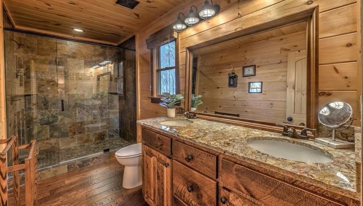 Guest bathroom featuring a walk-in stone shower, rustic wood vanity, and warm cabin finishes for a spa-like mountain experience.