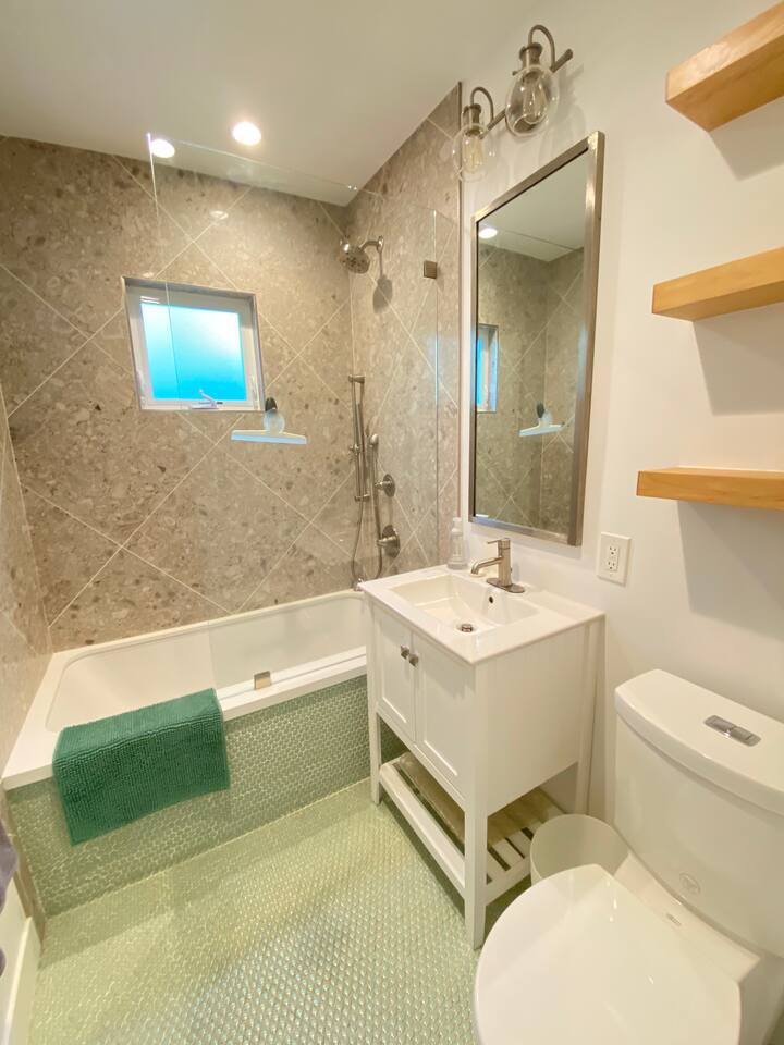 Clean and modern bathroom with a tub and rainfall shower.