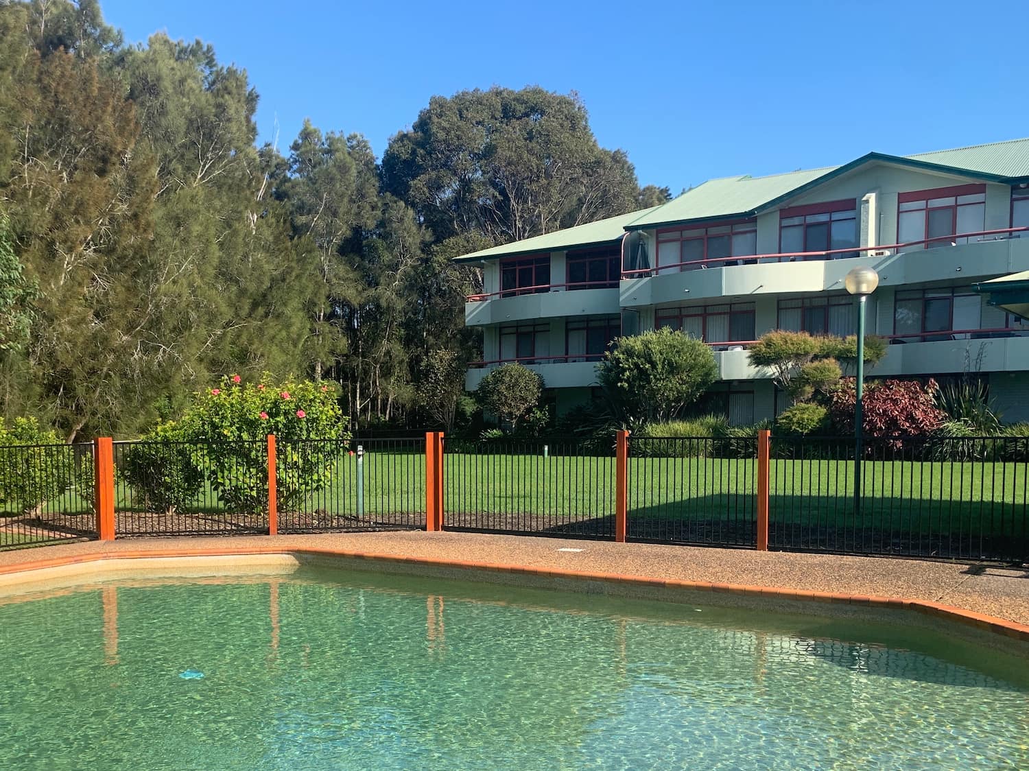 Fathoms pool with clear water, pool fence, blue sky & part of Fathoms building visible in the background