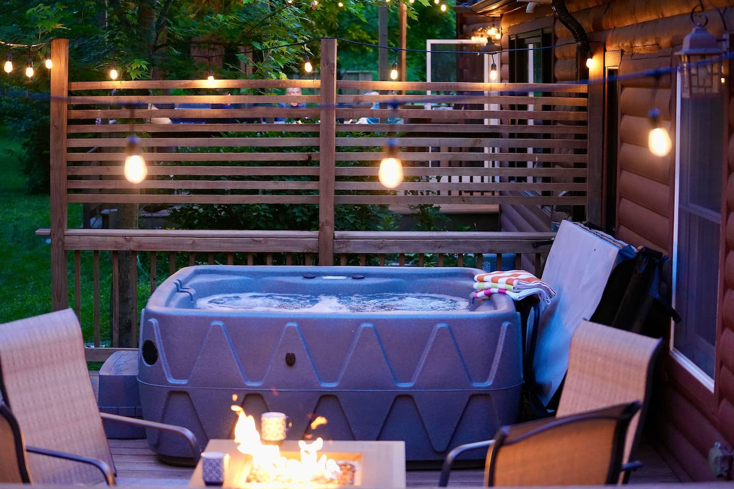 The fire and cafe lights provide a warm inviting atmosphere to this deck.