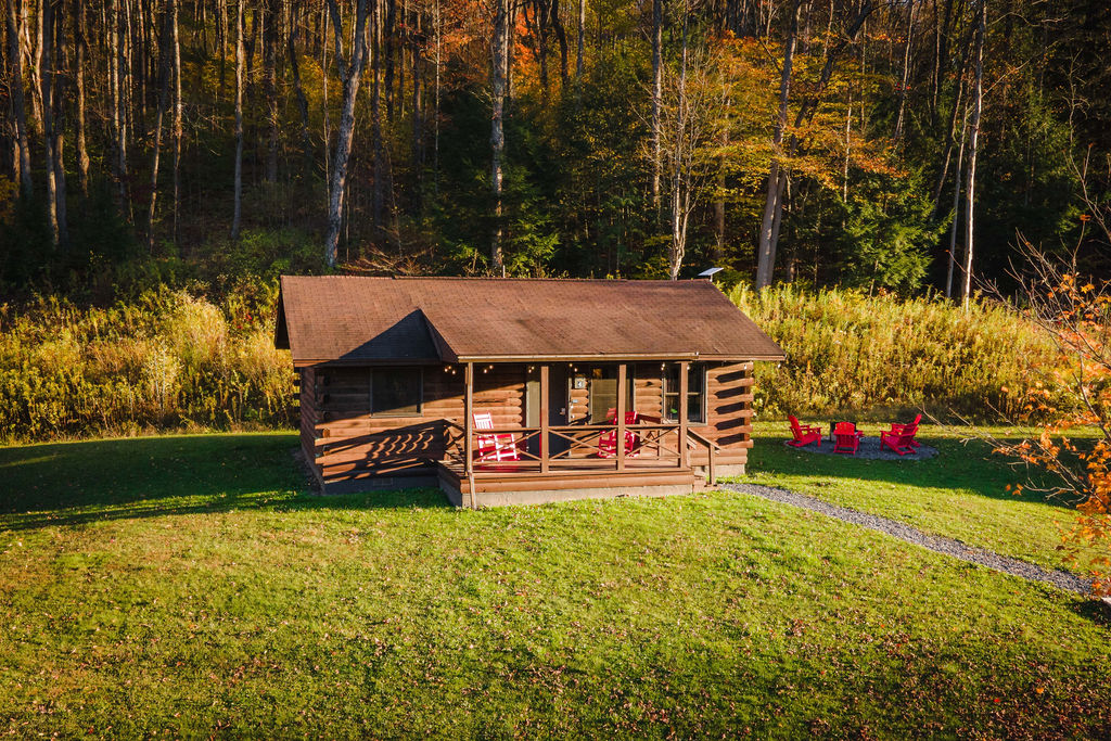 Private log cabin with porch seating and a fire pit out back — everything you need for a cozy mountain escape.