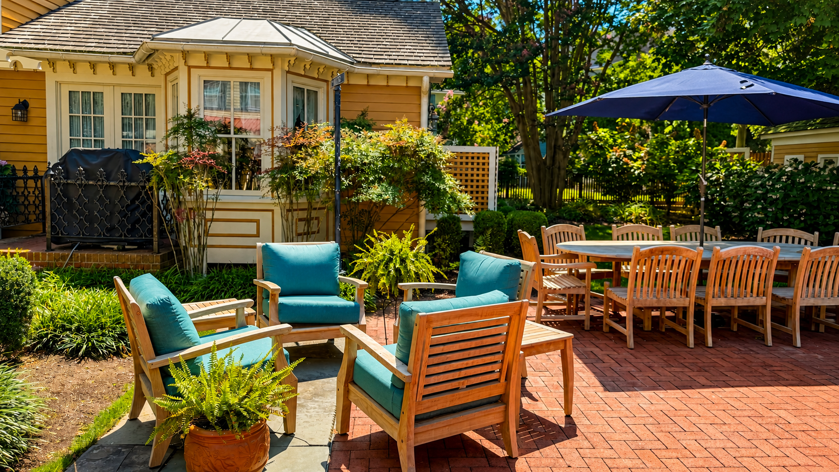 The private rear patio — teak seating, outdoor dining for the full group, and a gas grill tucked in the garden. Fully fenced and completely yours for the stay