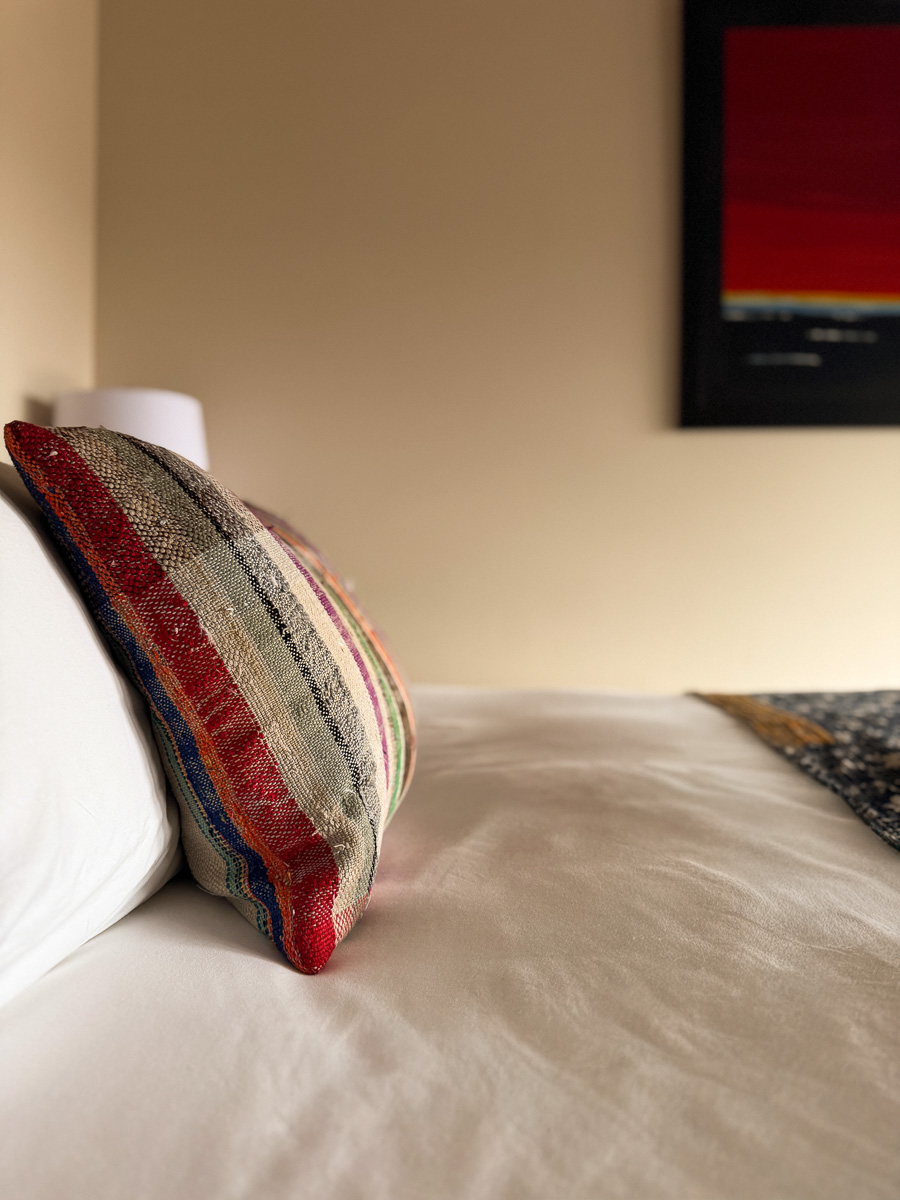 Pillow detail in a Sunset Falls guest room &mdash; handmade textile, a different one in each room