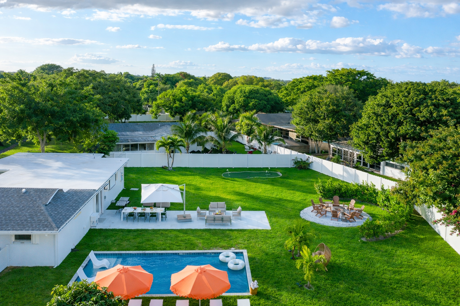 Private Palm Beach backyard with heated saltwater pool, fire pit, mini golf putting green, and outdoor lounge seating.