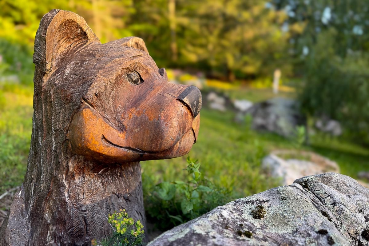 Hand-carved wooden bear on a mossy rock along the summer trail &mdash; Sunset Falls Berkshires