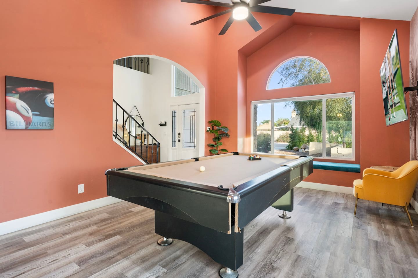 Recreation room with pool table, vibrant coral walls, arched entryway, and stunning outdoor views.