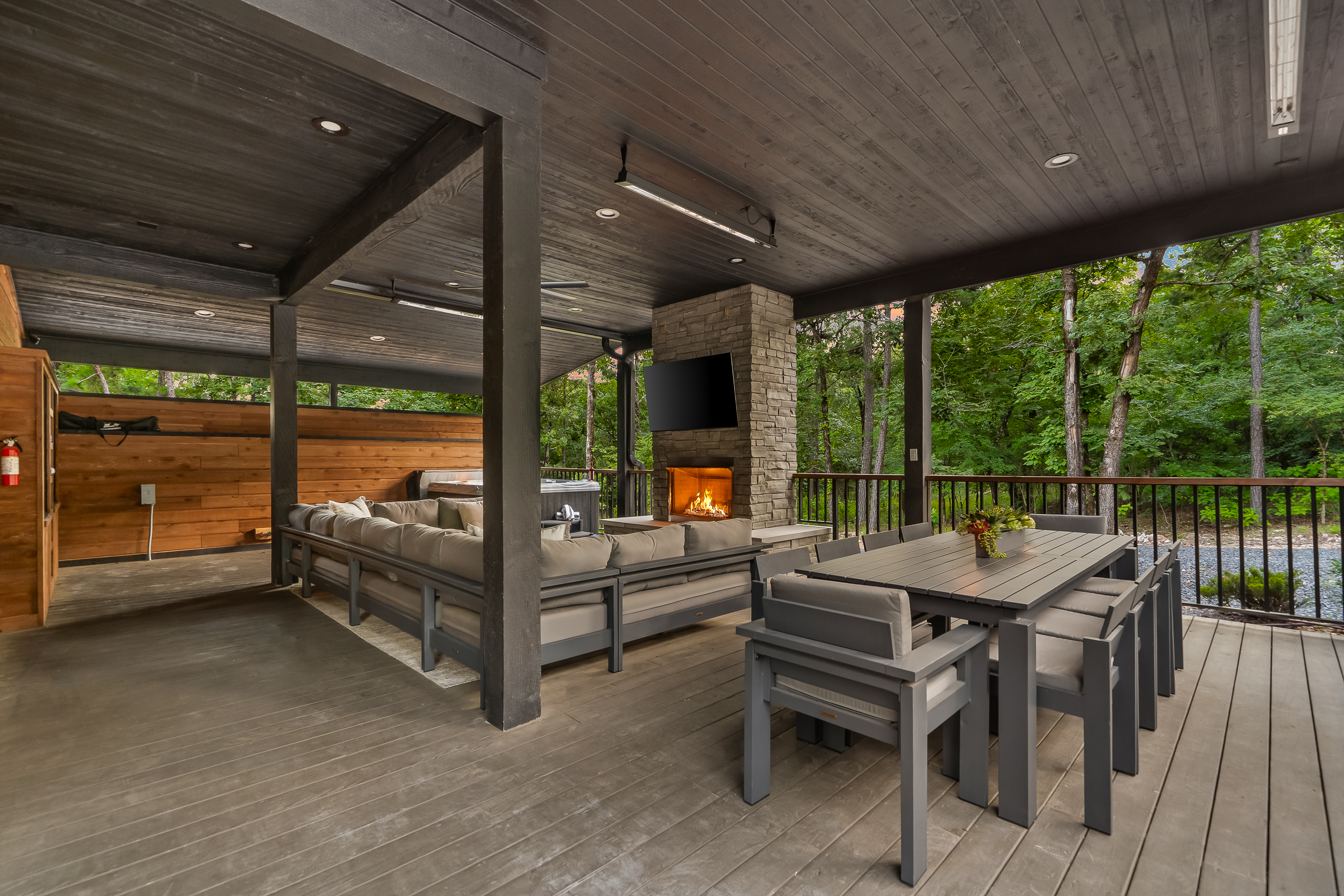 Large covered patio includes a gas fireplace, hot tub, smart TV, large spacious sectional, and outdoor dining area. Includes infrared heaters included as an extra bonus for all-weather enjoyment!