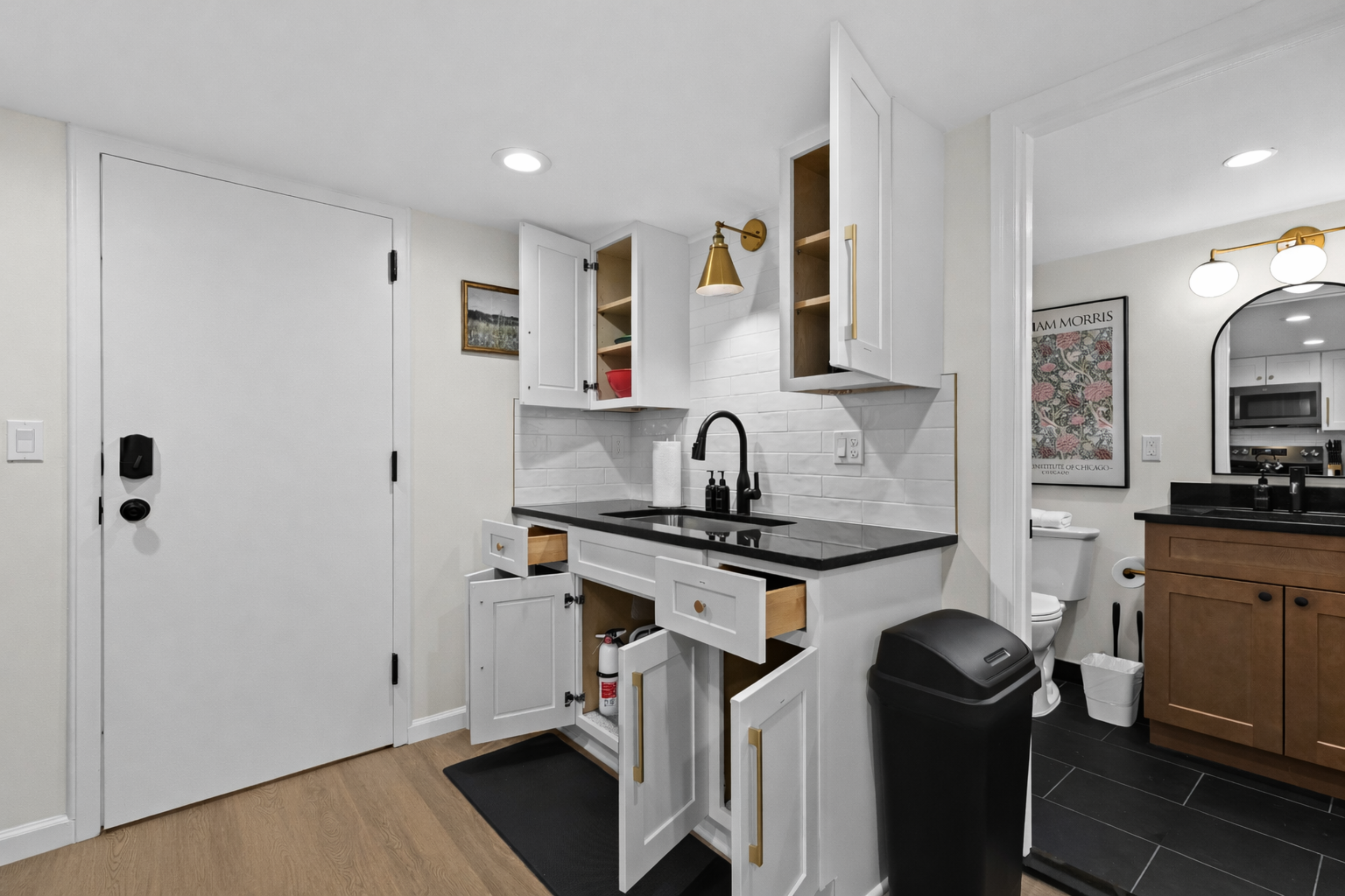 Efficient kitchenette with generous storage featuring sleek cabinetry, black countertops, and modern fixtures—designed to keep everything organized and within easy reach.