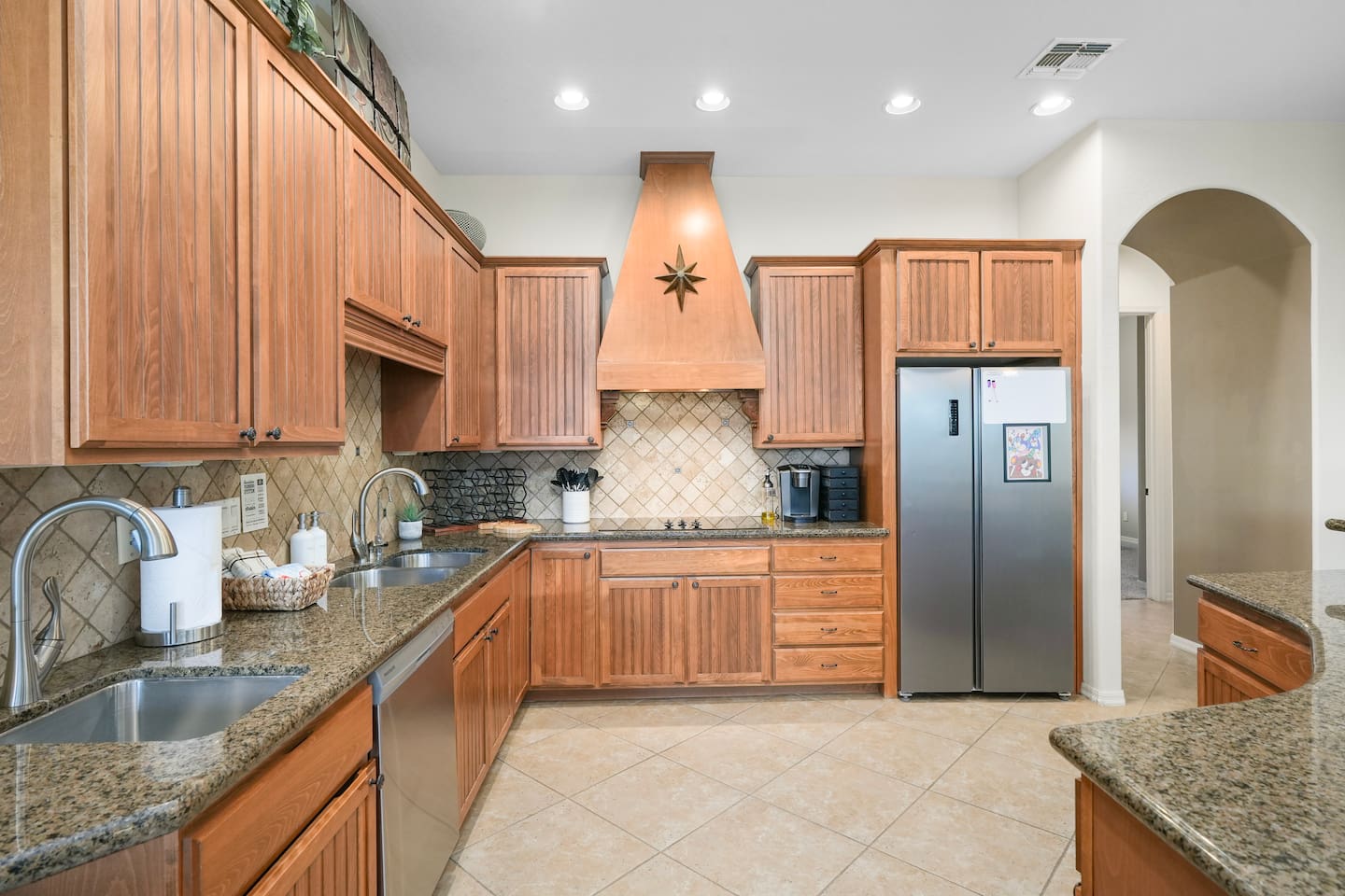 Warm wood cabinetry paired with granite counters and modern lighting.